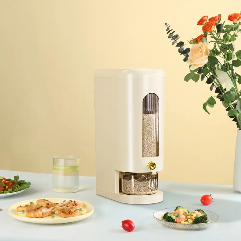 The 10kg automatic rice dispenser storage container on a table surrounded by plates of food and flowers to the side.