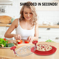 The chicken breast shredder in red resting on a bench top in a kitchen. A women chopping a red bell pepper and a plate of various vegetables to the left.