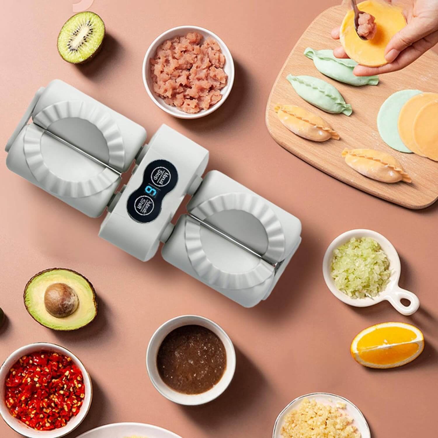 A birds eye view of the dumpling maker machine on a table surrounded by dumplings, food and condiments.