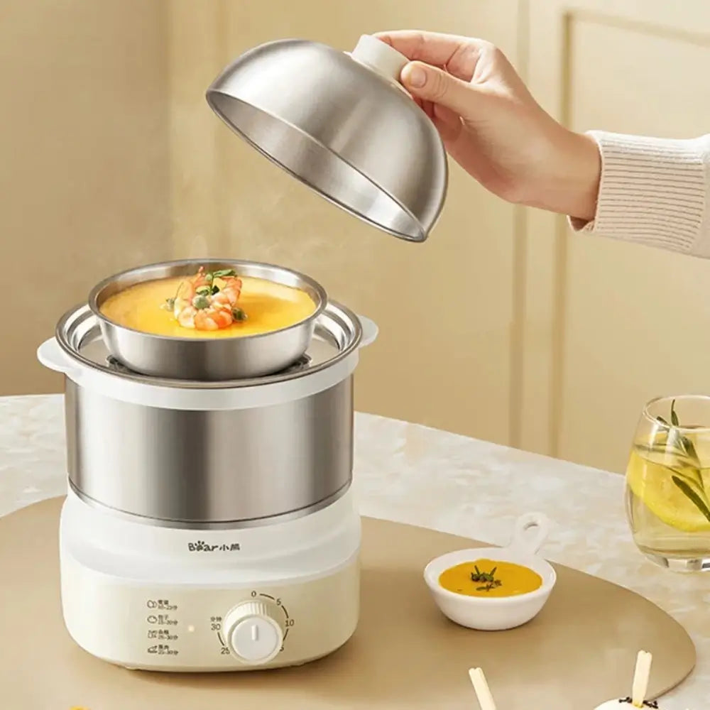 The egg boiler machine sitting on a table next to a bowl of soup. Someone removing the lid of the machine to reveal a shrimp soup being cooked.