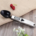 The electronic measuring spoon resting on a table.