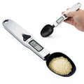 2 of the electronic measuring spoons. One filled and an empty one being held by someone.