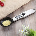 The electronic measuring spoon filled, resting on a table.