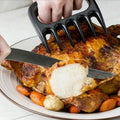 Someone using a meat shredder claw to hold a roast chicken while cutting into it with a knife.